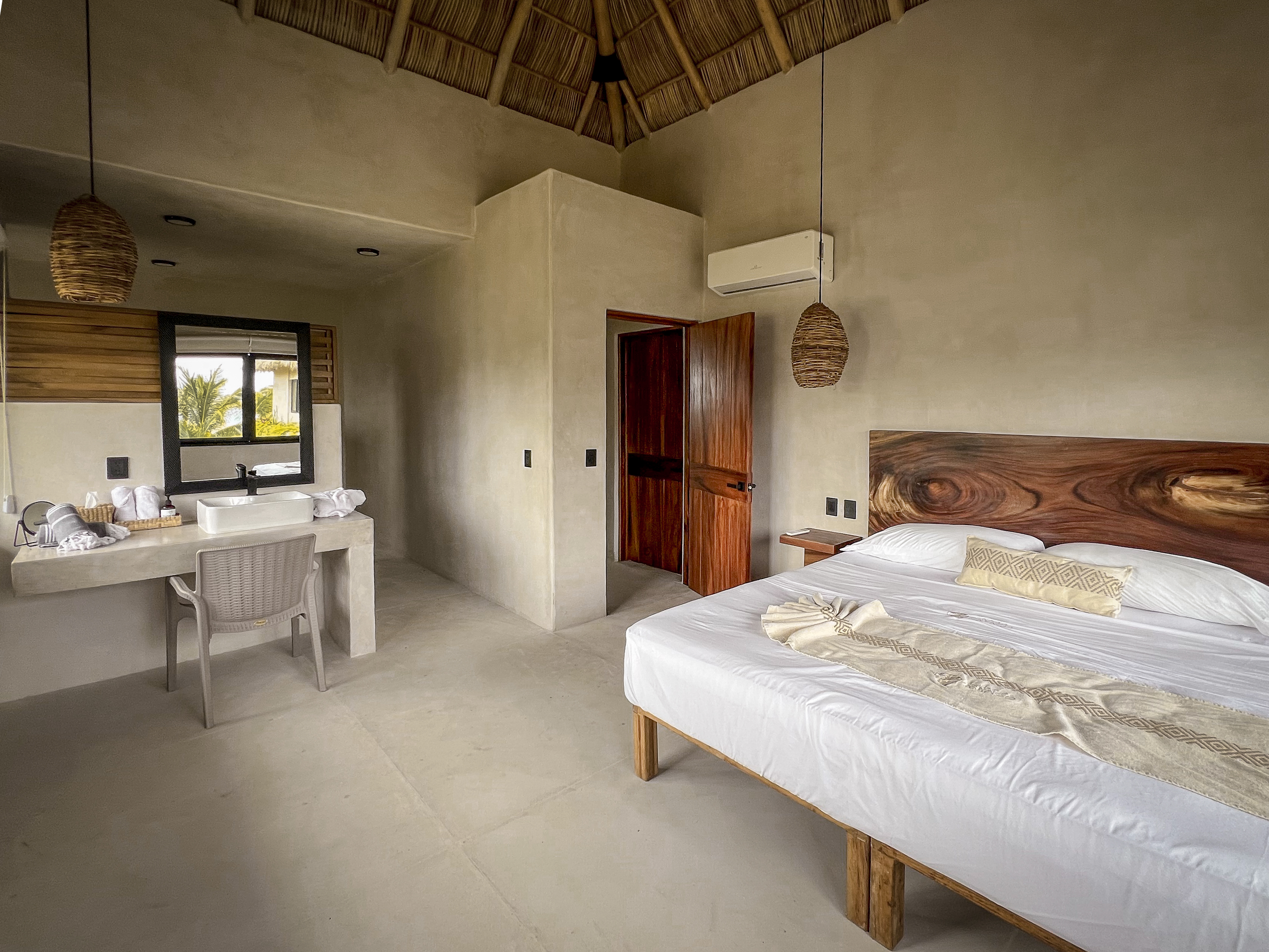 Suite principal con techo de palma, cama de parota y tocador