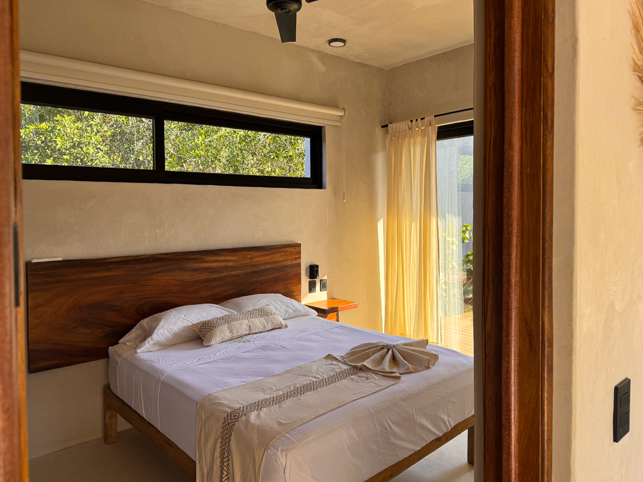 Recámara con cama de parota y ventana a la vegetación